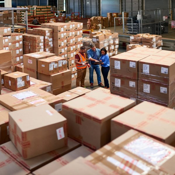 three people consulting in distribution warehouse