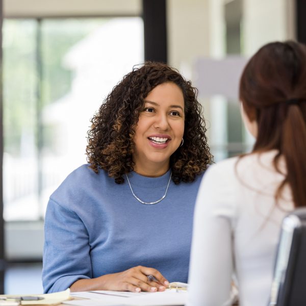 An unrecognizable woman and her mid adult female co-worker meet to brainstorm ideas for their upcoming presentation.