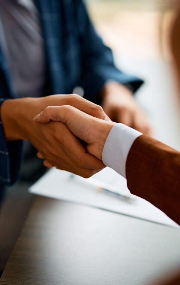 Close up of coworkers handshaking while greeting during business meeting in the office.