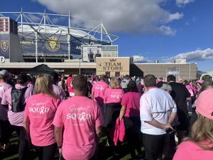 Crowd in pink shirts at an outdoor event near the Utah Royals' stadium team store.