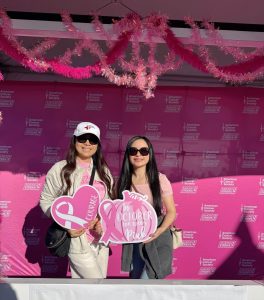 Two women at an American Cancer Society event holding pink signs supporting breast cancer awareness.