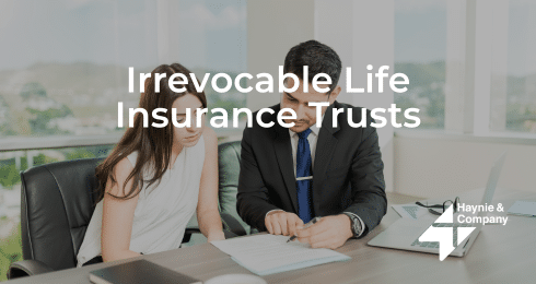 Man and woman discussing documents labeled Irrevocable Life Insurance Trusts in an office setting.