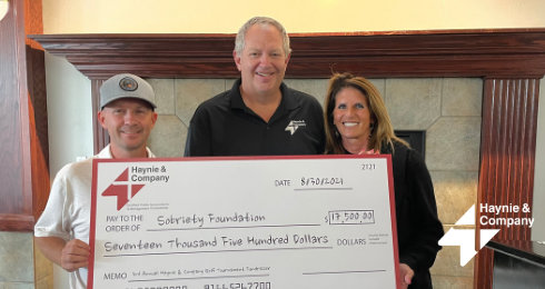 Three people holding a large check for $17,500 from Haynie to the Sobriety Foundation.