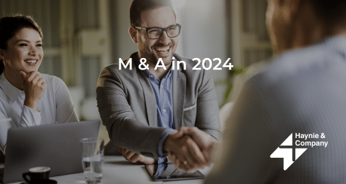 Business professionals shaking hands at a meeting table, discussing M&A in 2024.