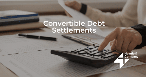 A person calculating finances with focus on convertible debt settlements.
