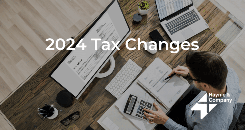 2024 Tax Changes text over a desk with computer, paperwork, and calculator, Haynie logo.