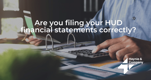 Man using calculator and laptop for HUD financial statements, Haynie logo.