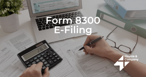 Form 8300 E-Filing: Person using calculator and laptop for tax document.