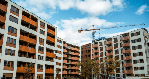 Apartment buildings with a construction crane in the background under a partly cloudy sky.