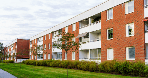 Modern brick apartment building with balconies and landscaped greenery.