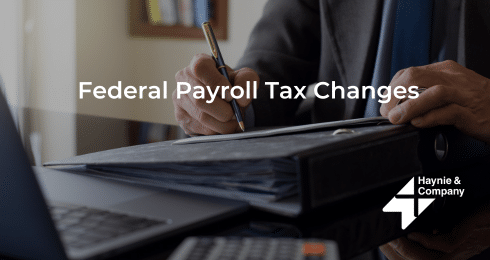 Federal Payroll Tax Changes document being reviewed by a person at a desk with a laptop.