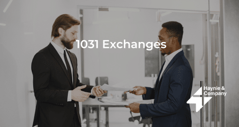 Two businessmen discussing 1031 exchanges in an office setting, wearing suits and exchanging documents.