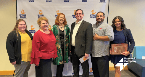 Group photo at a Special Reach event with seven people smiling in front of a branded backdrop.