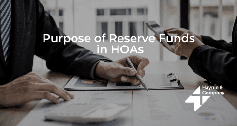 Two people discussing HOA reserve funds with documents and pen.