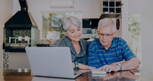 Senior couple using a laptop and taking notes at home.