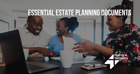 People discussing estate planning documents at a table with laptops and cups.