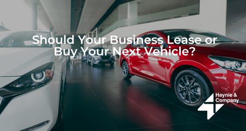 Car dealership interior with multiple vehicles and query about leasing or buying for business. Haynie logo present.