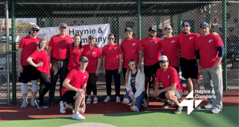 Haynie team in red shirts at a sports event standing in front of a banner.