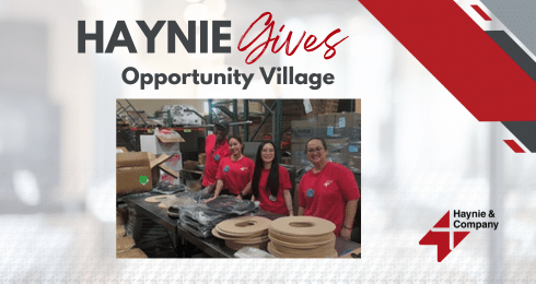 Haynie volunteers at Opportunity Village event, assembling materials and smiling in the warehouse.