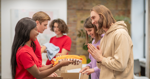 People exchanging clothes at a donation event, smiling and interacting warmly.