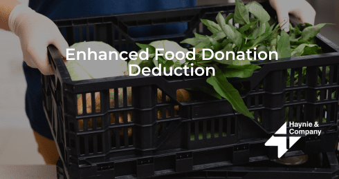Hands holding a crate of fresh produce with Enhanced Food Donation Deduction text overlay.