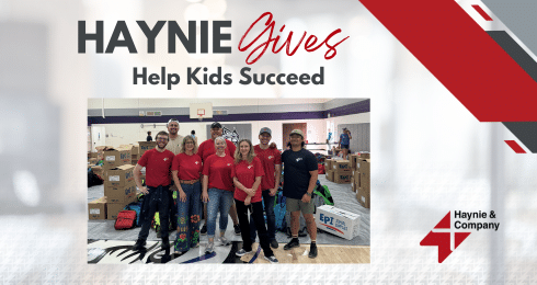 Group of people in red shirts volunteering at an event with Haynie Gives and Help Kids Succeed text.