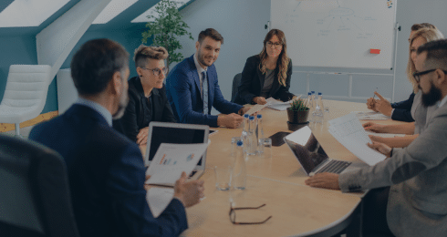 Business meeting in a conference room with people discussing around a table.