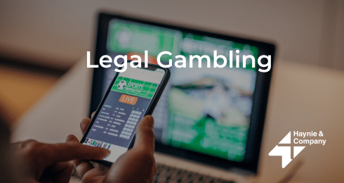 Legal gambling concept with mobile betting app and laptop screen in background.