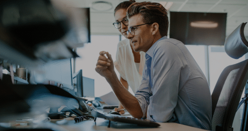 Professional teamwork discussion at desk with computers in modern office.