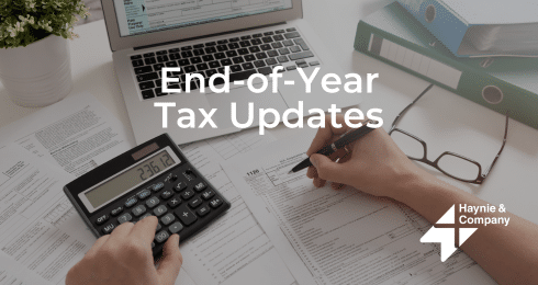 Calculating taxes with a calculator and forms, End-of-Year Tax Updates text overlay, by Haynie.