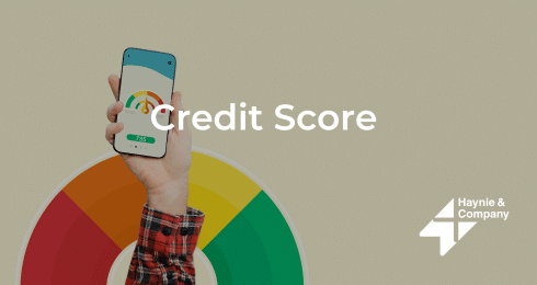 Hand holding phone with credit score app, colorful gauge, Haynie logo.