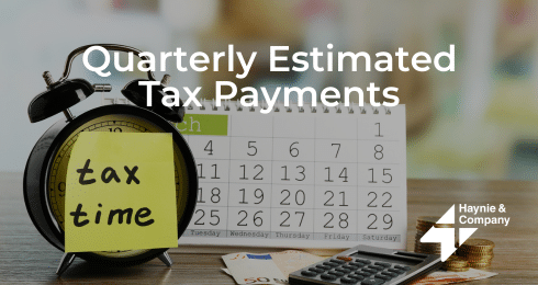 Quarterly estimated tax payments concept with calendar, clock, calculator, and currency on a desk.