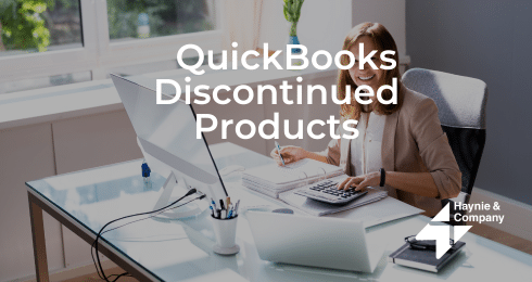 A woman at a desk using a calculator and computer, text reads QuickBooks Discontinued Products.