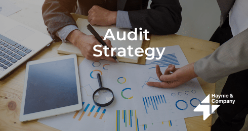 Two people discussing audit strategy with charts and tablet on desk.