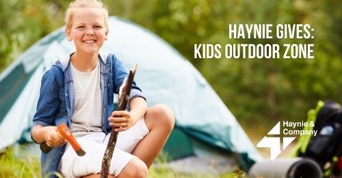 Child enjoying outdoor camping with a tent in the background.