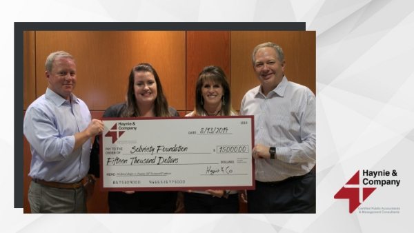 Four people holding a $15,000 Haynie check for Schwing Foundation donation.