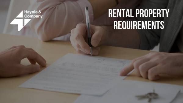 Signing rental agreement with keys on table, text Rental Property Requirements.