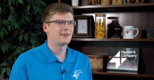 Man in glasses wearing a blue polo shirt with Haynie logo in an office setting.