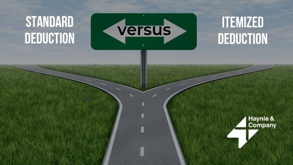 Road split symbolizing choice between standard and itemized tax deductions with direction sign.