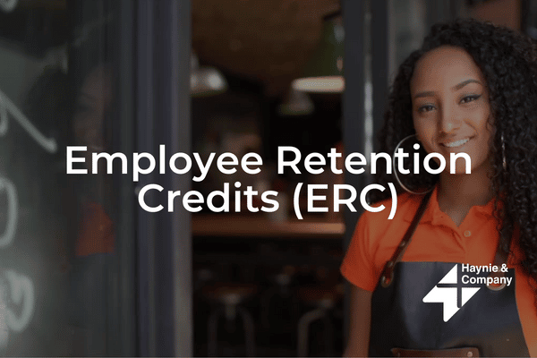 Employee standing in front of storefront, smiling, with text “Employee Retention Credits (ERC)” and Haynie logo.