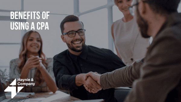 A group of professionals in a meeting, with two men shaking hands, discussing CPA benefits.