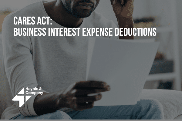 Person reading about CARES Act: Business Interest Expense Deductions with Haynie logo.