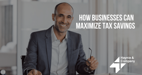 A man in a business suit holds glasses, with How Businesses Can Maximize Tax Savings text.