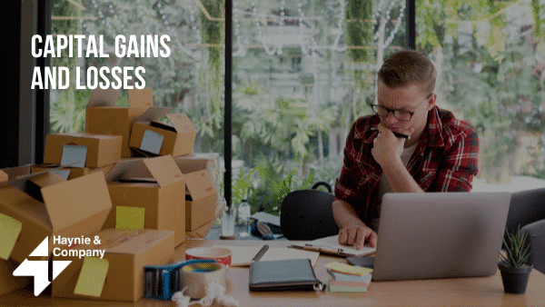 Man analyzing capital gains and losses on laptop at home office with boxes.