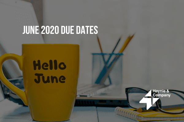 Yellow mug with Hello June text beside glasses and a notebook on a desk.