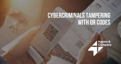 Person scanning QR code on paper with phone; text: Cybercriminals Tampering with QR Codes.