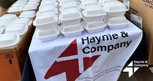 Haynie table with stacked white food containers at event.