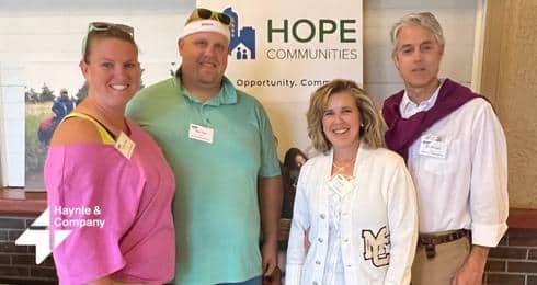 Four people smiling in front of a Hope Communities banner at a networking event.
