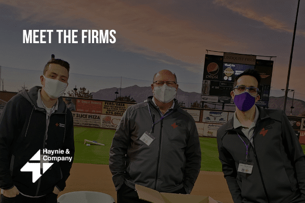 Three people at a Meet the Firms event at a baseball field, wearing masks, representing Haynie.
