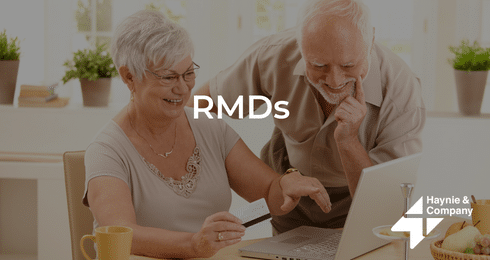 Older couple reviewing RMDs on a laptop in a brightly lit kitchen.